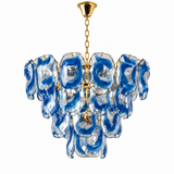 A tiered glass chandelier featuring swirling blue and clear glass shades suspended from a gold-toned chain and canopy, shown against a plain white background.