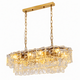 Linear chandelier with tiered clear textured glass, gold-tone chains and canopy, and glowing lights against a white background.