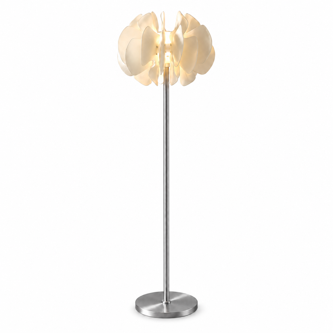 A modern floor lamp with a tall silver metal stem and a flower-shaped white shade that glows with warm light, set against a plain white background.