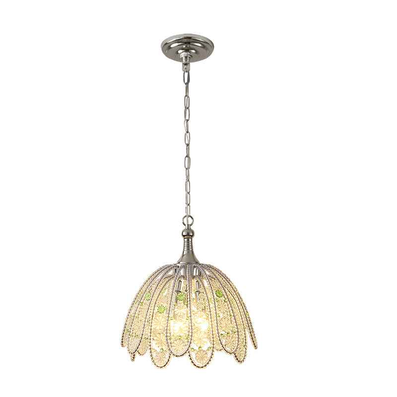 Illuminated chandelier with clear glass petals, green floral accents, and a silver-toned chain against a white background.