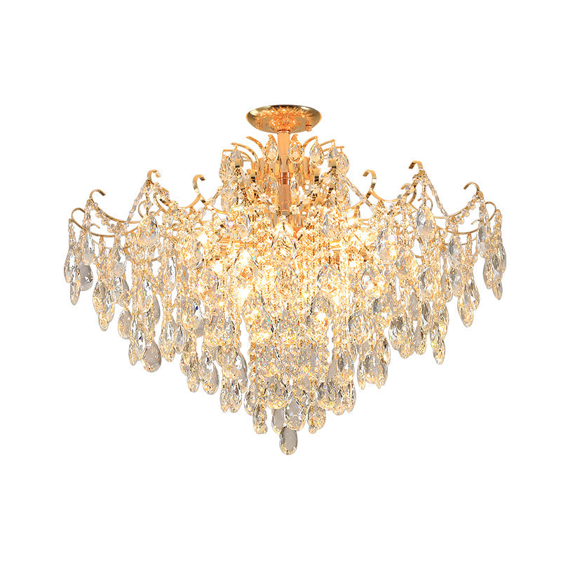 Gold-tone chandelier with curved arms and tiers of clear teardrop pendants, illuminated against a white background.