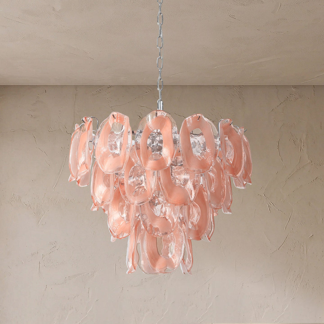 Tiered chandelier with pink and clear glass loops hangs from a silver chain against a textured beige wall.