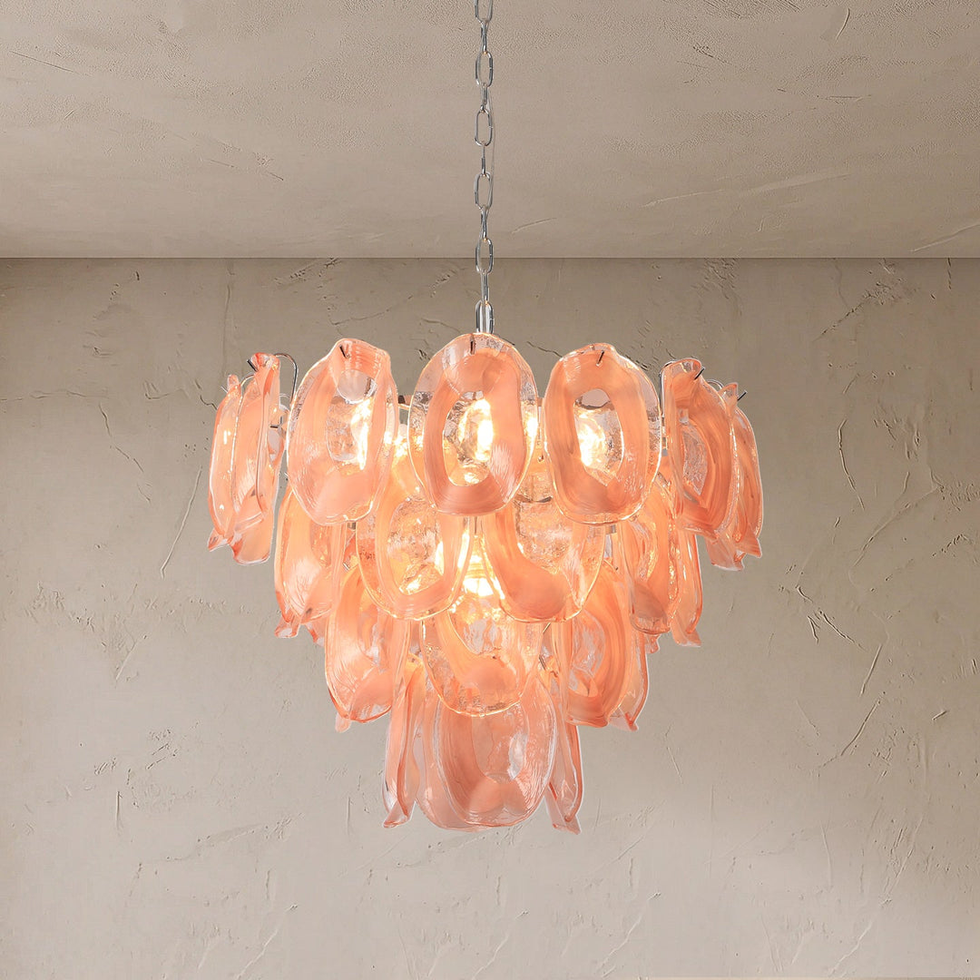 A modern cluster chandelier with translucent peach-pink glass petal-like shades hanging from a silver chain against a textured beige wall and ceiling.