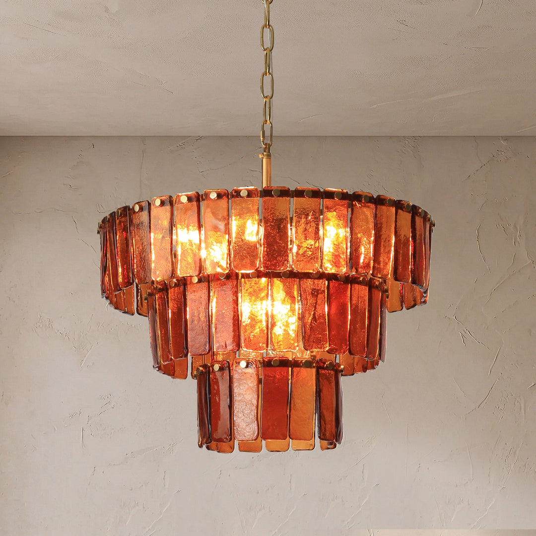 A tiered chandelier with rectangular amber-orange glass shades and a gold-toned chain, shown hanging against a textured off-white wall.