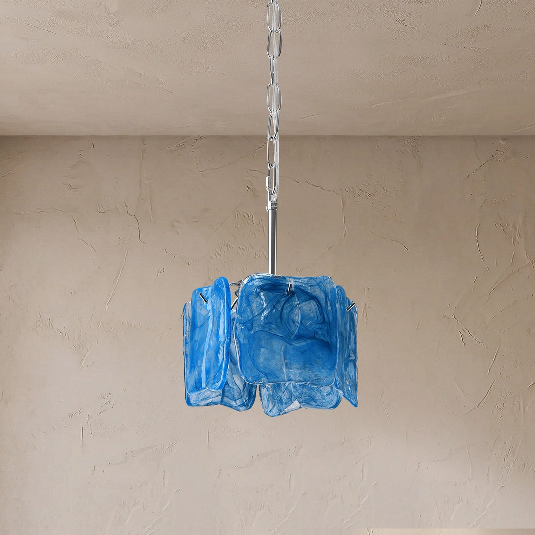 A blue textured glass pendant light hanging from a silver metal rod and chain against a beige plaster wall and ceiling.