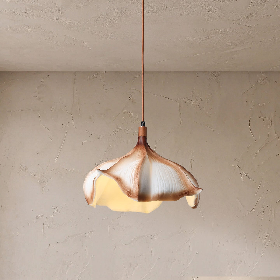 A sculptural pendant light shaped like a garlic bulb, suspended from a thin cord against a textured plaster wall and ceiling.