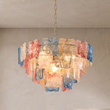 A modern chandelier with multiple layers of translucent, hand-blown glass panels in blue, pink, and peach tones, suspended from a chain against a textured beige wall and ceiling.