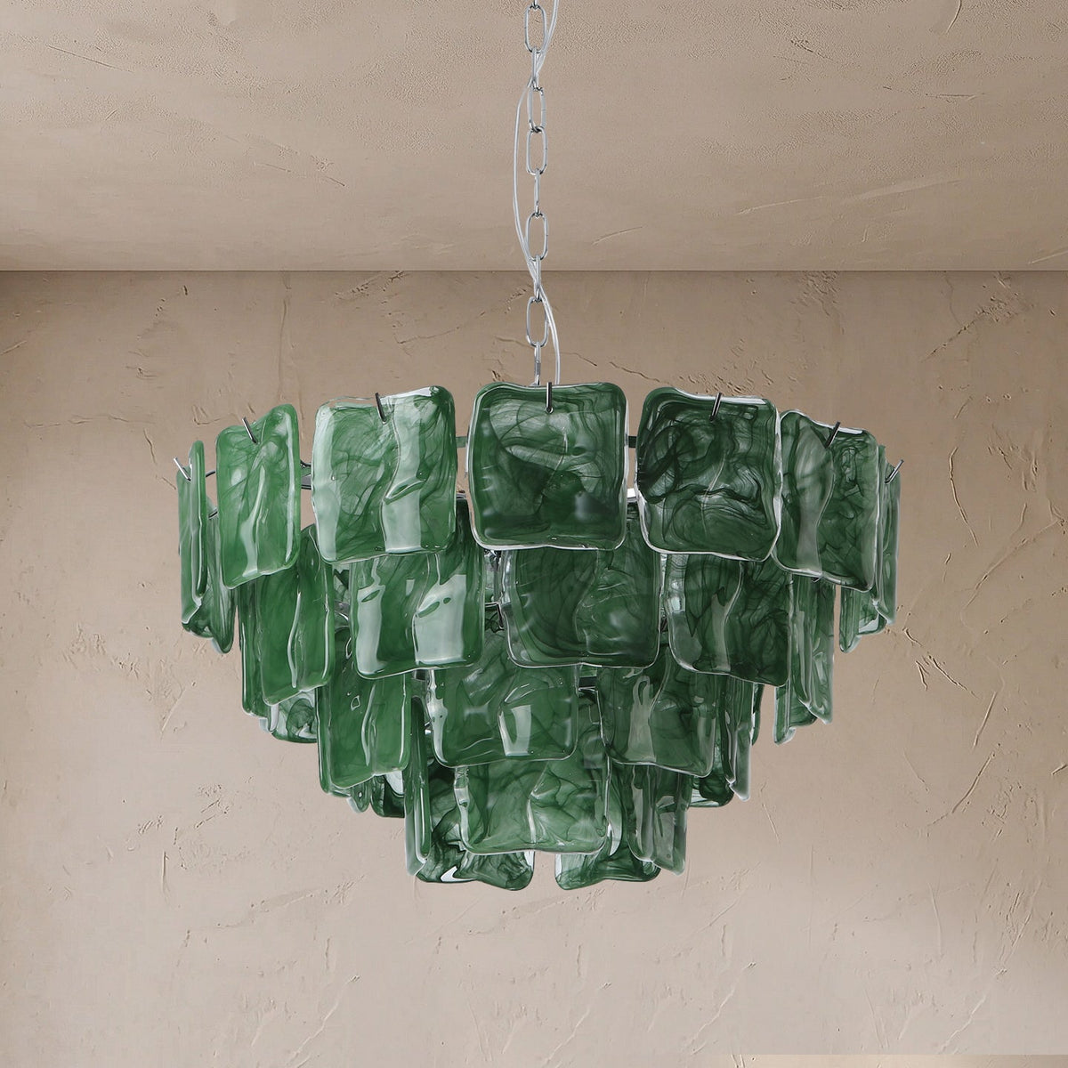 A green glass chandelier with multiple square-shaped translucent shades, suspended from a chain against a textured beige plaster wall and ceiling.