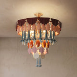 Illuminated chandelier with gold ceiling mount and tiered burgundy, pink, blue, and orange decorative pendants against a textured beige ceiling.