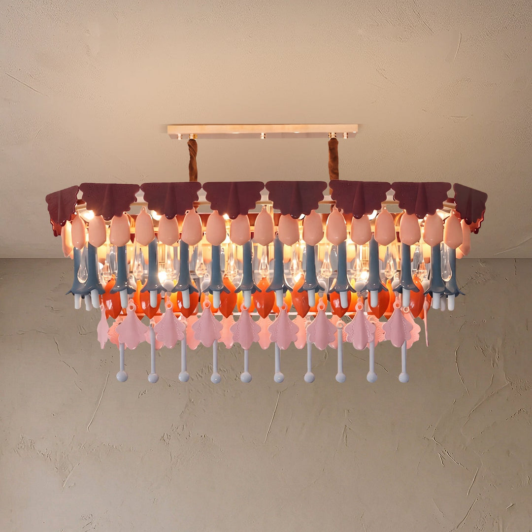 Illuminated rectangular chandelier with layered purple, pink, blue, orange, and clear hanging ornaments against a textured beige background.