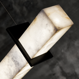 A close-up of the linear pendant light shows glowing, veined alabaster held by a black bracket against a dark background.