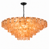A modern tiered chandelier featuring textured amber-orange glass rectangular shades suspended in a curved, cascading arrangement, with a black chain and ceiling canopy against a solid white background.