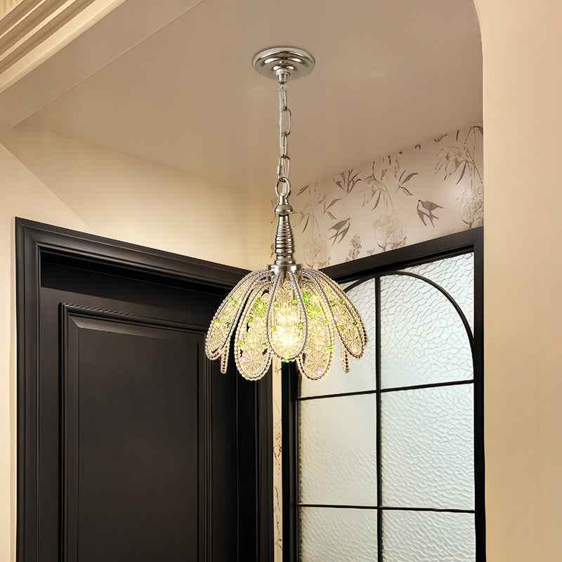 Glass petal chandelier with green accents glows warmly beside a dark door and black-framed textured glass window.