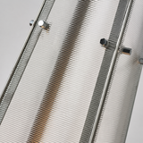 Close-up of the floor lamp’s clear ribbed acrylic shade, silver metal frame, and exposed fasteners against a light gray background.