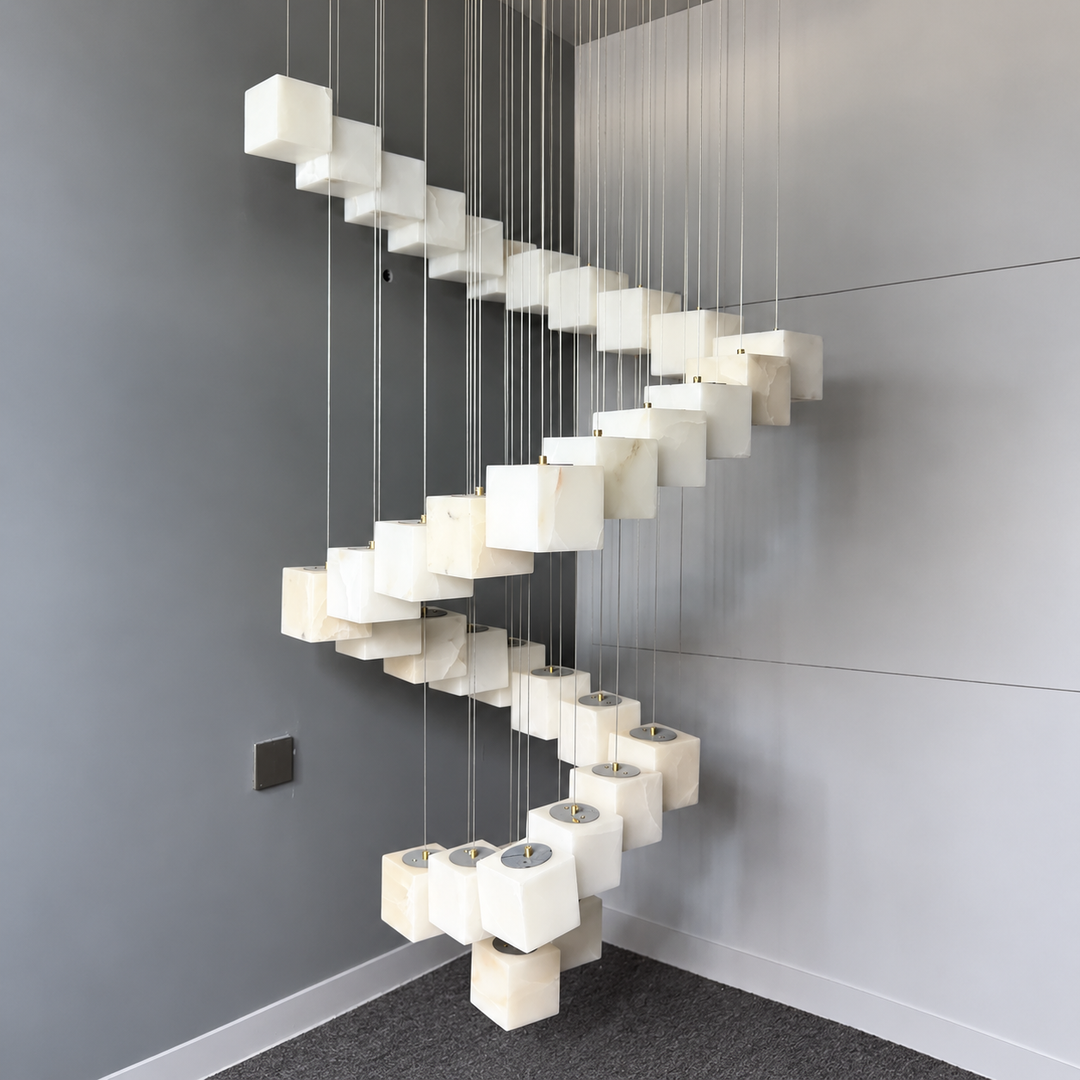 Chandelier with white alabaster cube shades suspended in a descending spiral against gray walls.