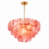 A modern drum-shaped pendant chandelier featuring textured, translucent pink glass discs that glow warmly from an integrated light, suspended from a polished gold-toned chain and ceiling canopy against a solid white background.