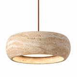 A modern pendant light fixture with a thick, rounded stone disc shade in a natural beige travertine texture, suspended by a slim brown cord against a solid white background.