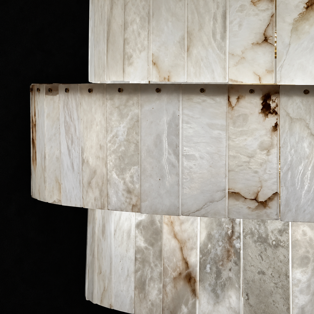 Close-up of a chandelier with overlapping tiers of cream alabaster panels and brown veining against a black background.