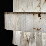 Close-up of a chandelier with overlapping tiers of cream alabaster panels and brown veining against a black background.