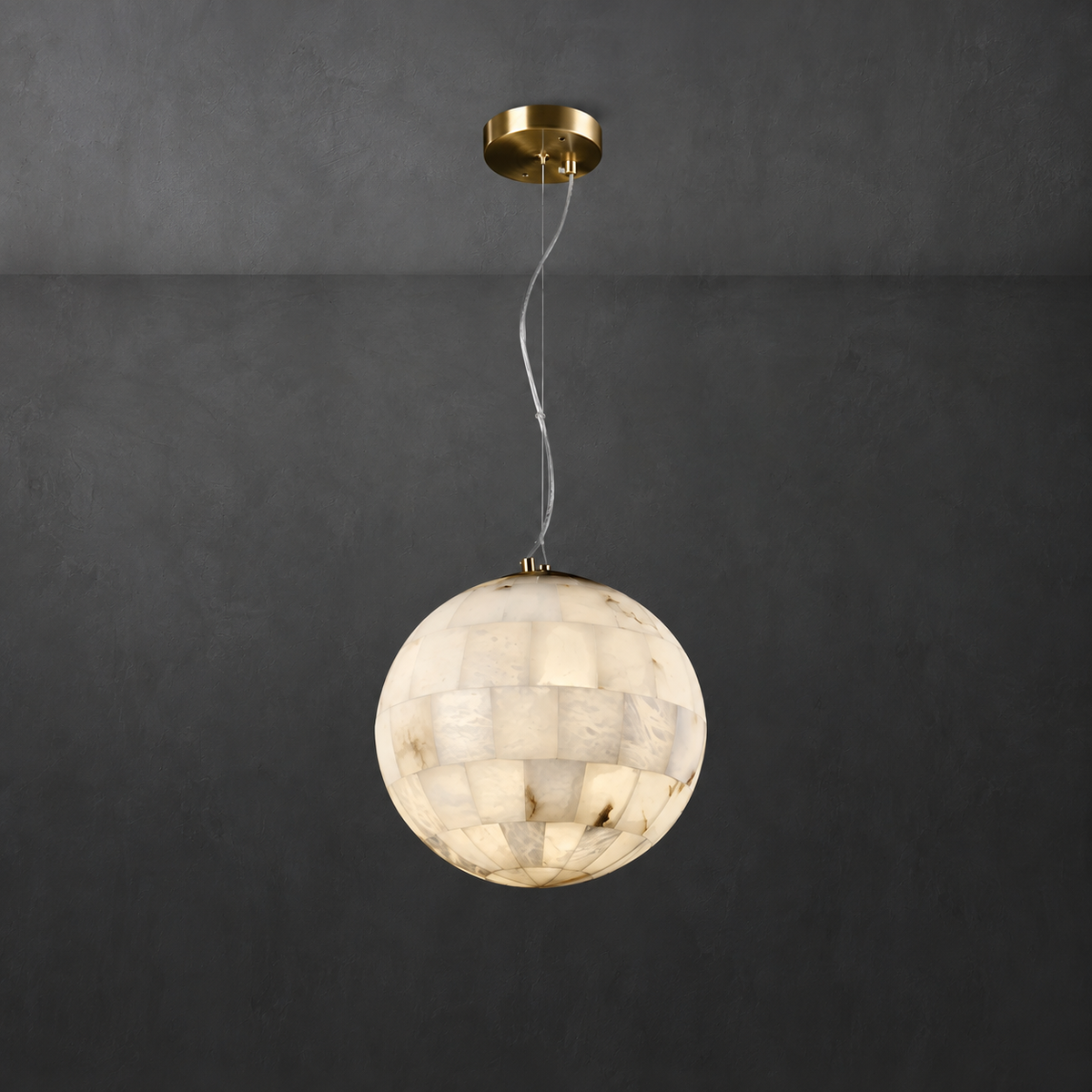 A spherical pendant light made of warm-toned stone or shell-like segments, suspended from a round gold ceiling canopy against a dark charcoal wall.