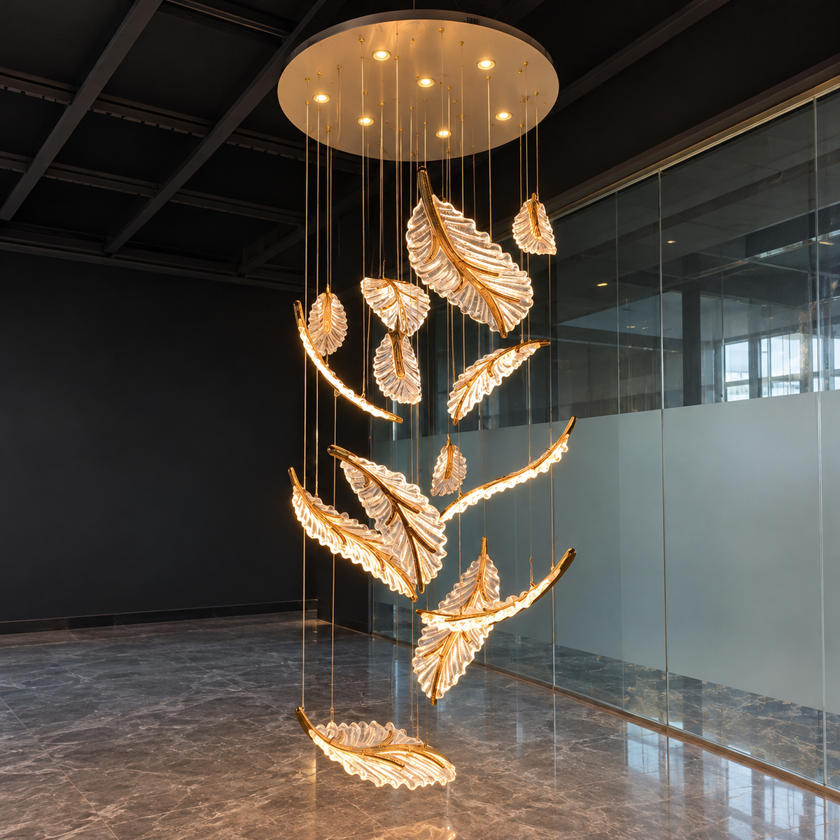 A modern multi-tier feather chandelier with a warm gold finish and illuminated white feather details, suspended from a circular ceiling mount in a contemporary office lobby.