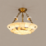 Illuminated semi-flush ceiling light with a cream alabaster bowl, brass chains, and decorative canopy against a plain beige background.