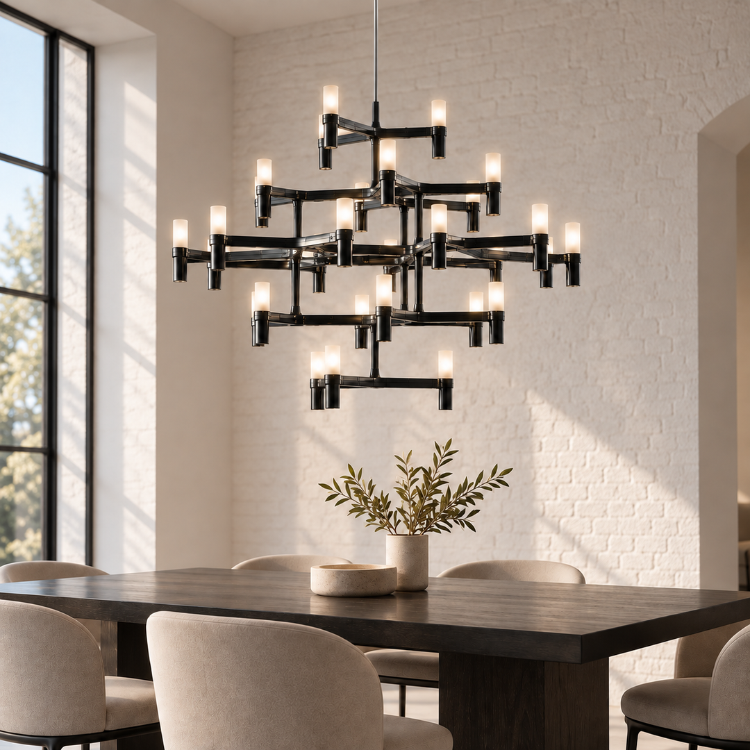 A modern multi-tier black metal chandelier with multiple candle-style bulbs hanging over a dark wood dining table in a bright dining room with white brick walls.