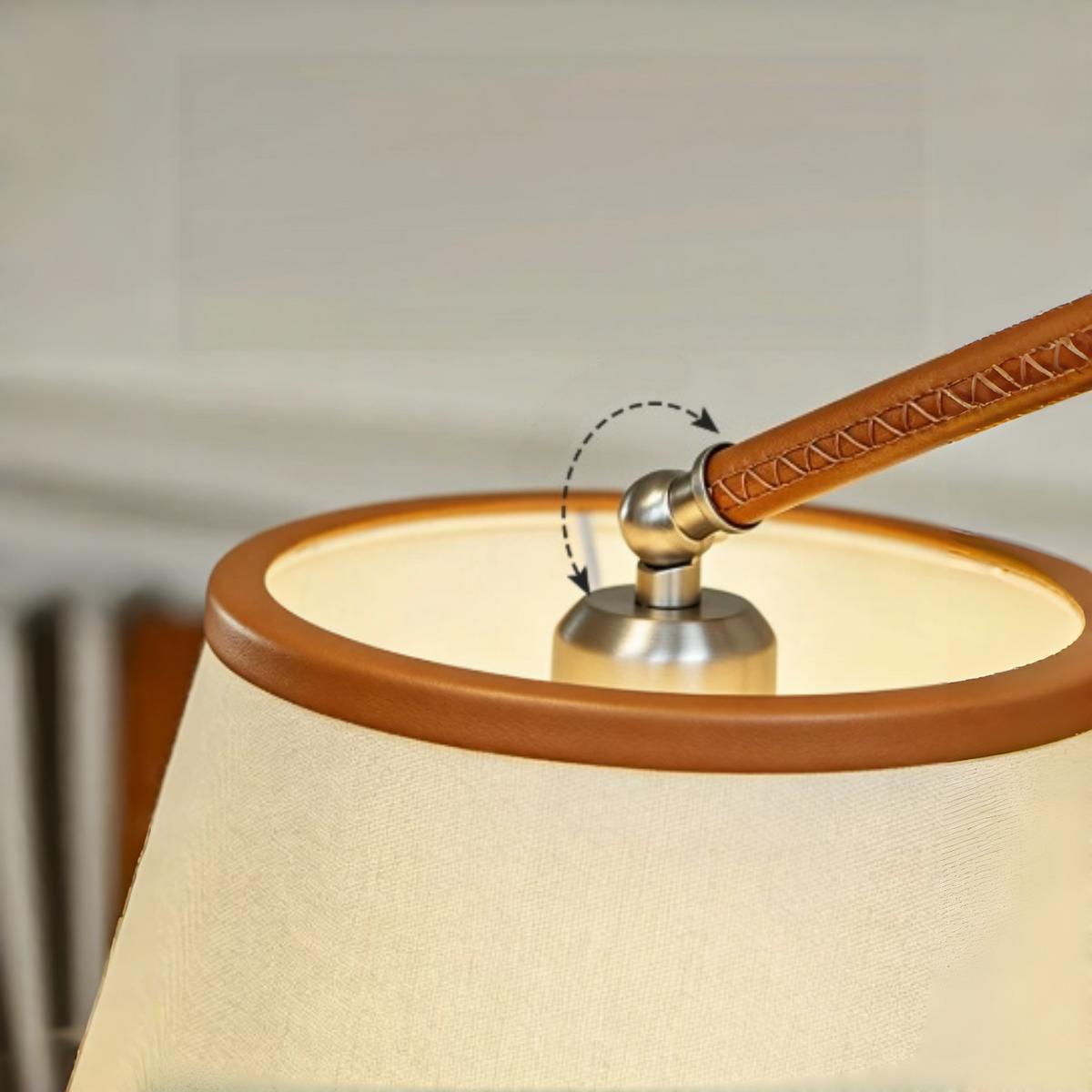 Close-up of the floor lamp’s cream fabric shade, brown leather trim and stitched arm, with a dotted arrow marking the silver joint.
