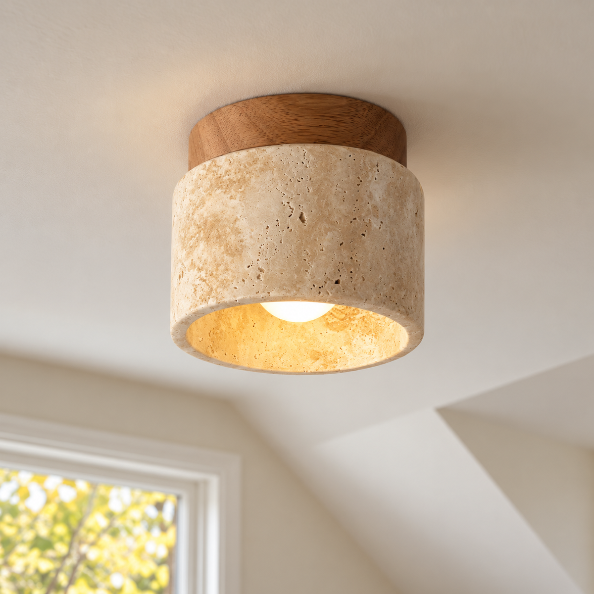 A modern semi-flush mount ceiling light fixture with a textured beige travertine stone shade and a natural wood top cap, shown illuminated on a white ceiling in a room setting.