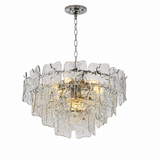 A modern multi-light pendant chandelier featuring a brushed silver metal chain and canopy, with a tiered ring of textured, irregular clear glass shades that glow warm yellow from the internal lights, set against a plain white background.