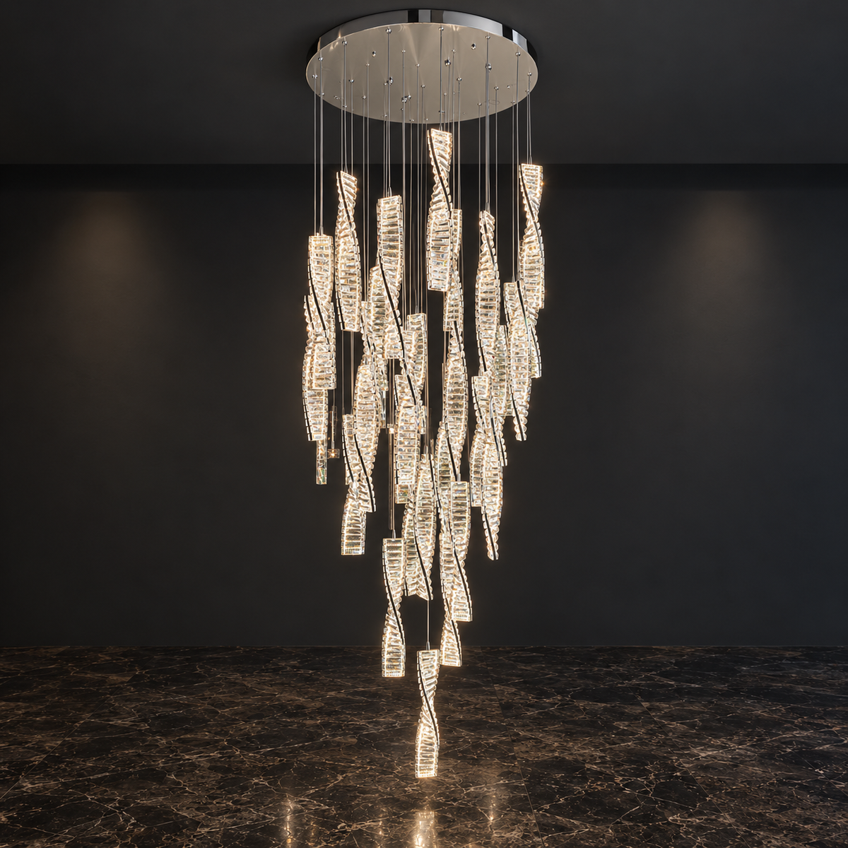 A modern multi-light chandelier with numerous illuminated crystal-like drop pendants suspended from a round silver ceiling canopy, shown hanging in a dark interior with a marble floor.