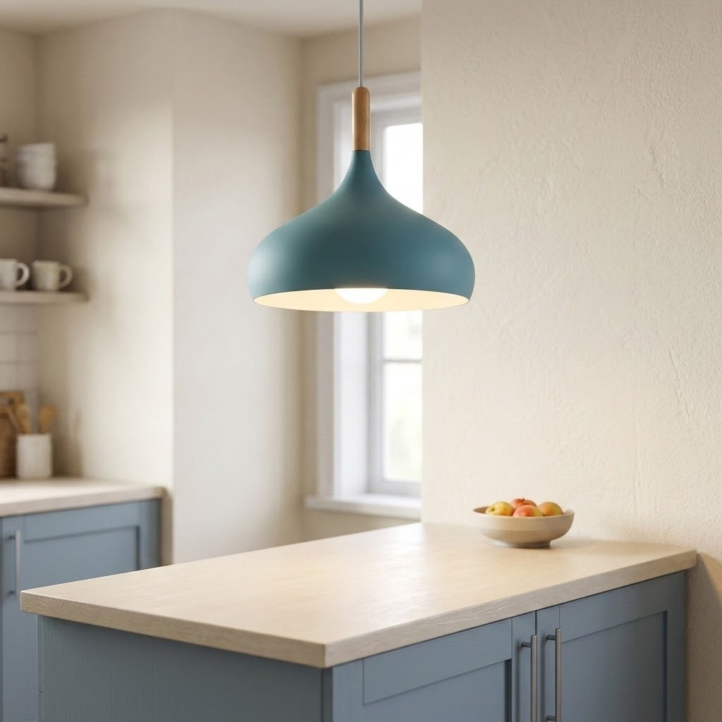 A modern teal pendant light with a natural wood neck hangs over a kitchen island with a light wood countertop and blue cabinets.