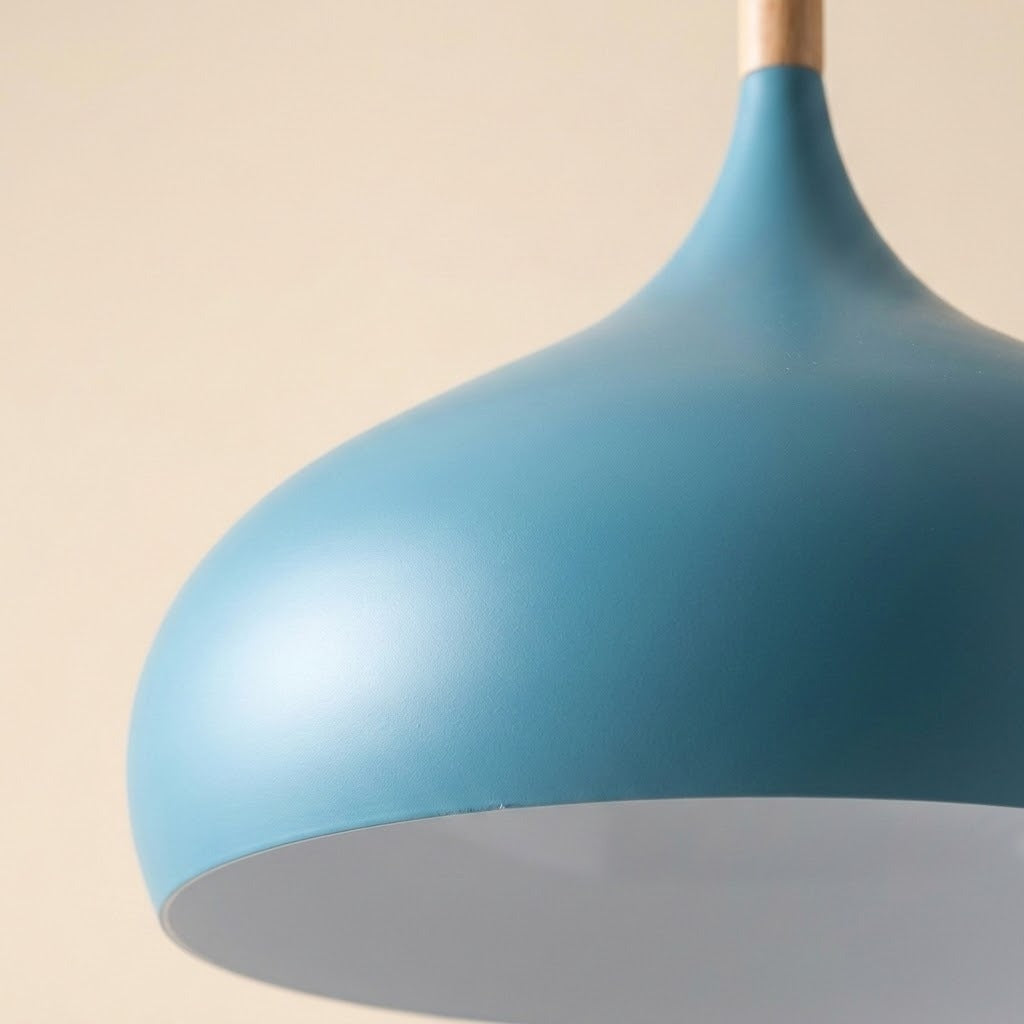 A close-up of a matte blue pendant light shade with a light wood hanging stem against a warm beige background.