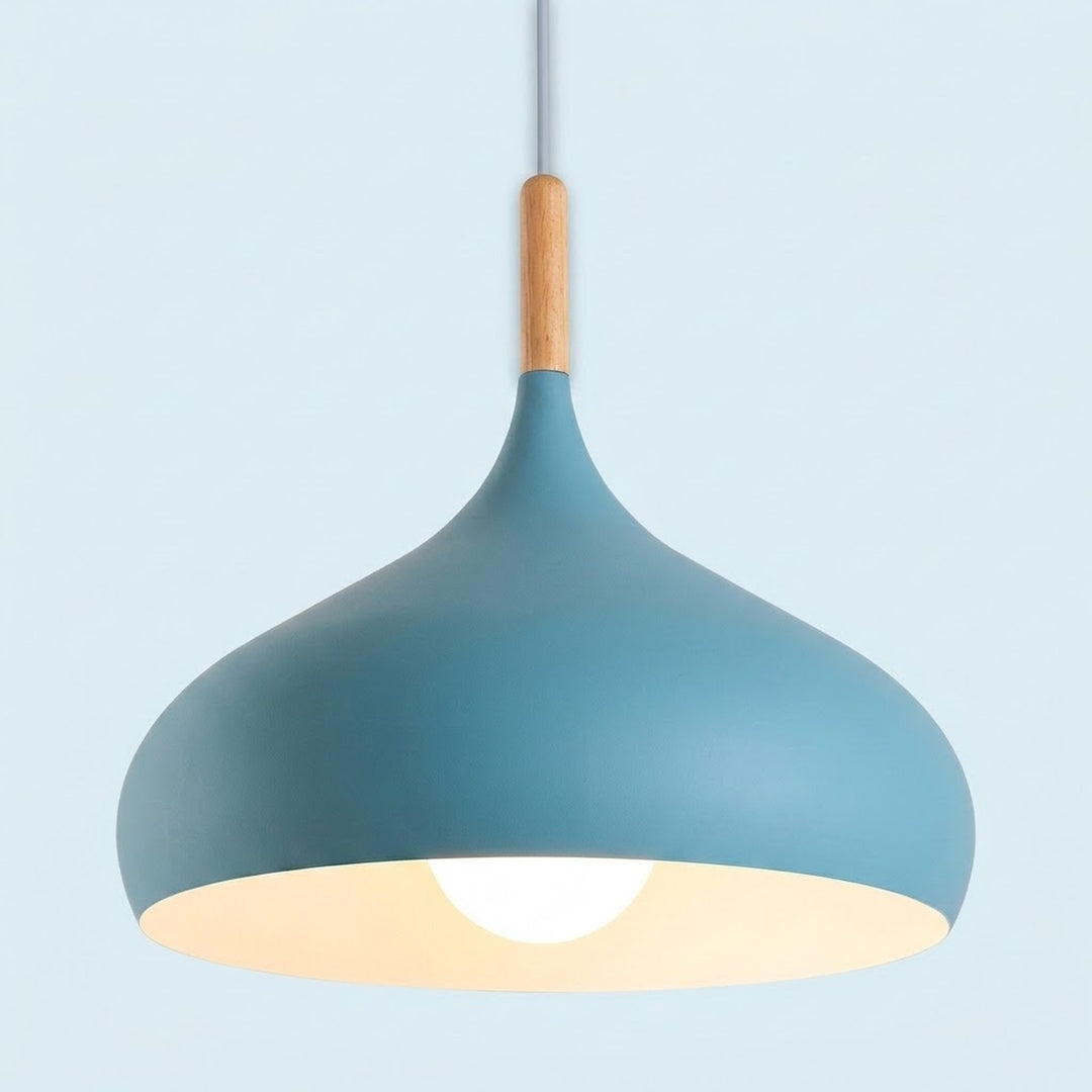 A modern pendant light with a matte blue-gray shade, a natural wood accent near the top, and a glowing warm white bulb inside, suspended against a pale blue background.