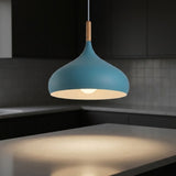 A modern pendant light with a matte blue dome-shaped shade, a light wood neck, and a glowing warm bulb inside, hanging over a kitchen island.