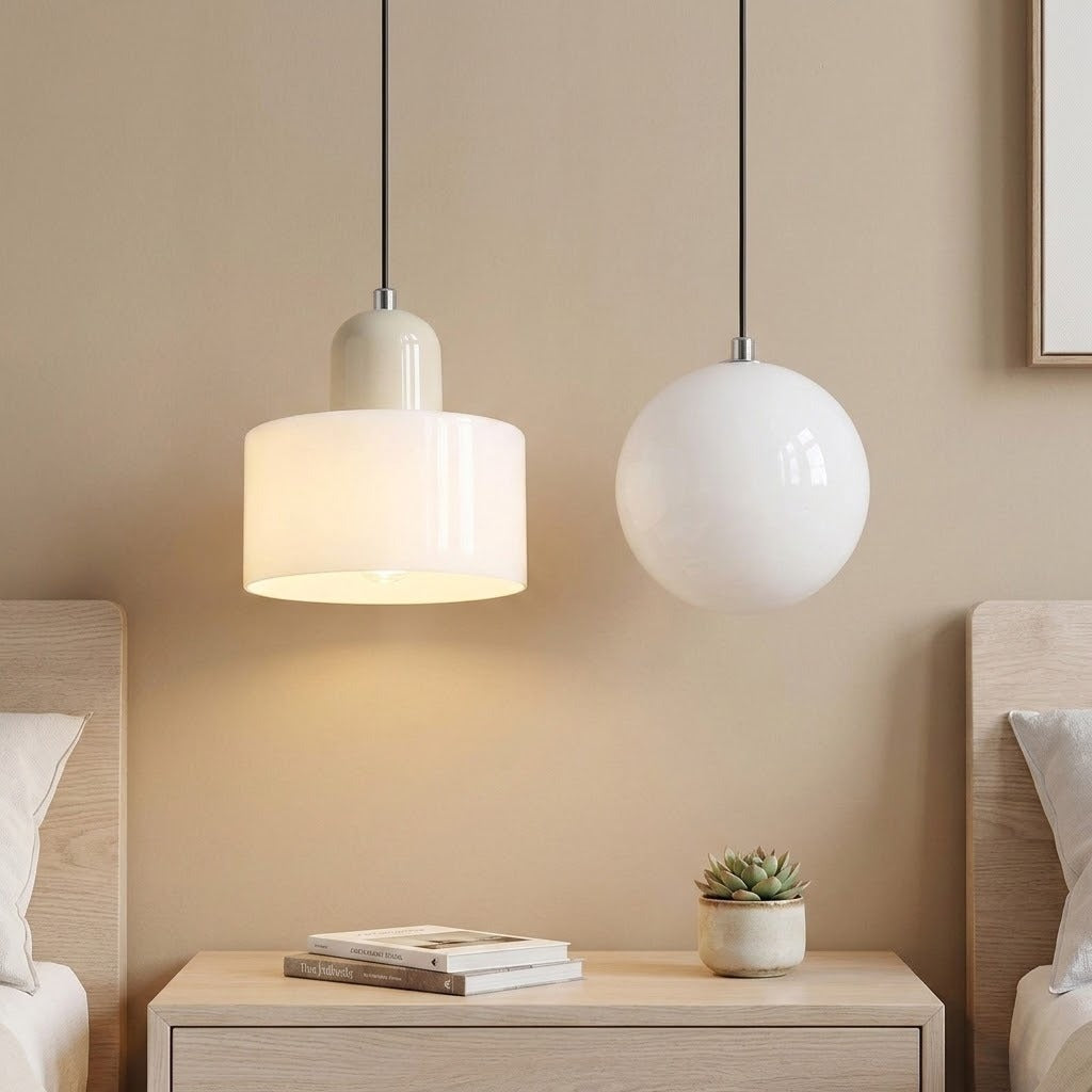 A white glass chandelier with a beige cap glows beside a white globe light above a shared nightstand between two beds.