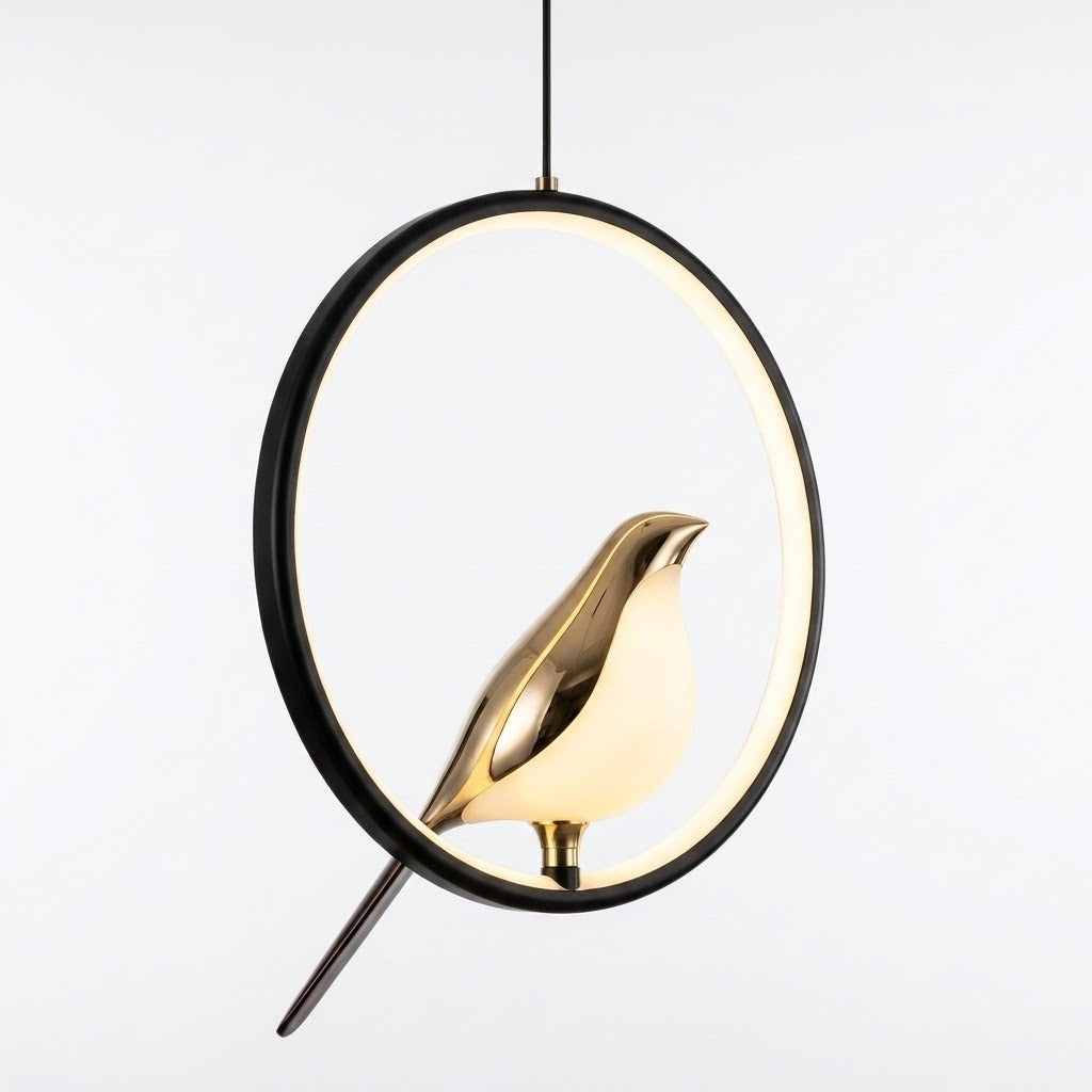 A modern pendant light featuring a polished gold bird-shaped shade suspended inside a black circular ring with a warm white glow, shown against a plain light gray background.