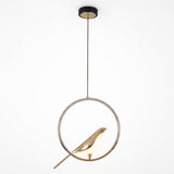 A modern pendant light fixture featuring a gold-toned bird silhouette inside a thin circular metal frame, suspended by a cord from a round black ceiling canopy against a plain white background.