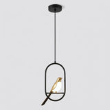 A modern pendant light fixture with a black metal frame and rod, featuring a small gold bird figurine with a glowing white light inside, suspended from a black ceiling canopy against a light gray background.