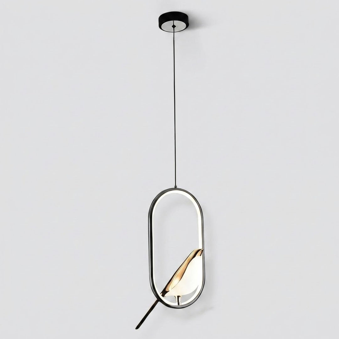 A modern pendant light fixture with a black circular ceiling canopy, a thin black suspension cord, and a geometric oval frame. Inside the frame, a warm-toned geometric shade or leaf-like element glows with a white diffuser, set against a plain light gray background.
