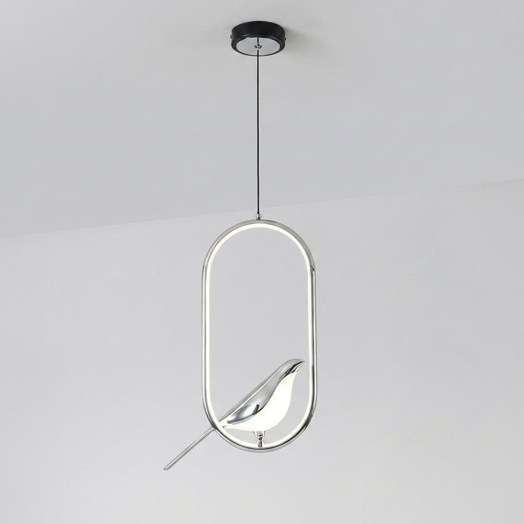 A modern pendant light fixture with a polished chrome oval frame and a sculptural bird-shaped shade, suspended by a thin cord from a black ceiling canopy against a plain white ceiling.