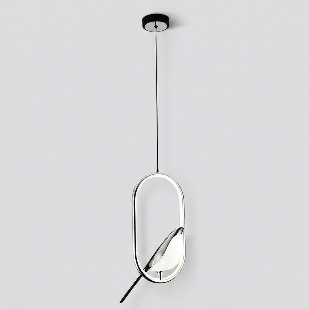 A modern pendant light fixture with a sleek oval frame, featuring a black ceiling canopy, a thin black suspension cord, and a reflective silver and black geometric body against a light gray background.