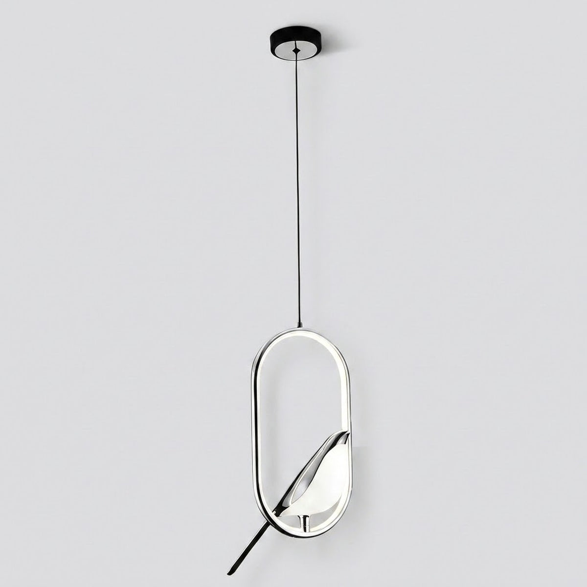A modern pendant light fixture with a sleek oval frame, featuring a black ceiling canopy, a thin black suspension cord, and a reflective silver and black geometric body against a light gray background.