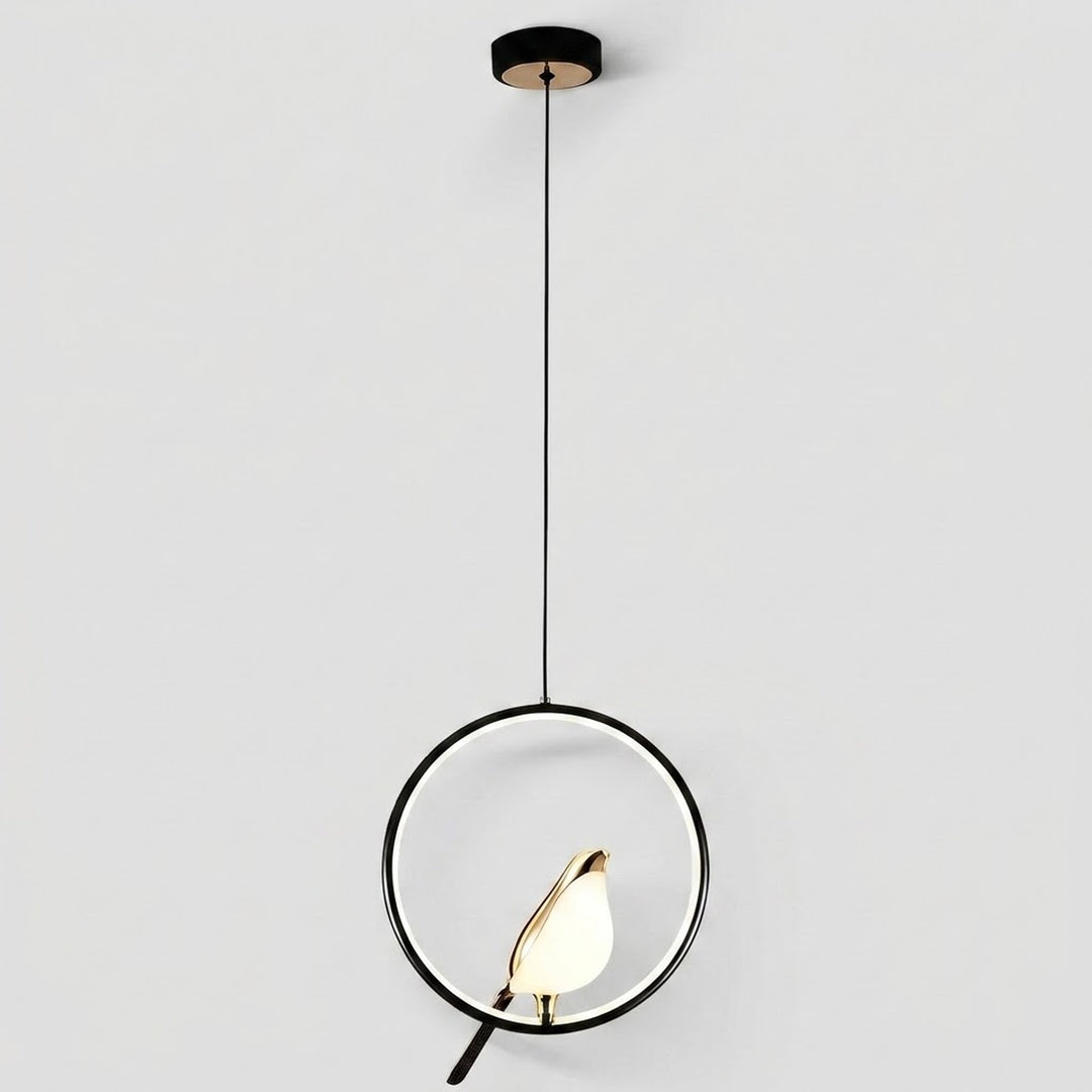 Modern pendant light with a black circular ring frame, a black cord, a black ceiling canopy, and a small gold-toned bird-shaped bulb holder containing a glowing warm white bulb, shown against a light gray background.