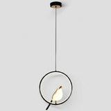Modern pendant light with a black circular frame, black cord, and a small gold bird-shaped shade holding a glowing white bulb, shown against a light gray background.