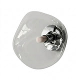Wall sconce with an irregular clear glass shade and polished silver mounting hardware stands alone against a white background.