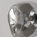 Close-up of a wall sconce showing its curved reflective glass shade, smooth edge, silver socket, and exposed bulb.