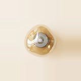 Amber glass wall sconce with a rounded triangular shade and circular silver fitting mounted on a pale cream wall.