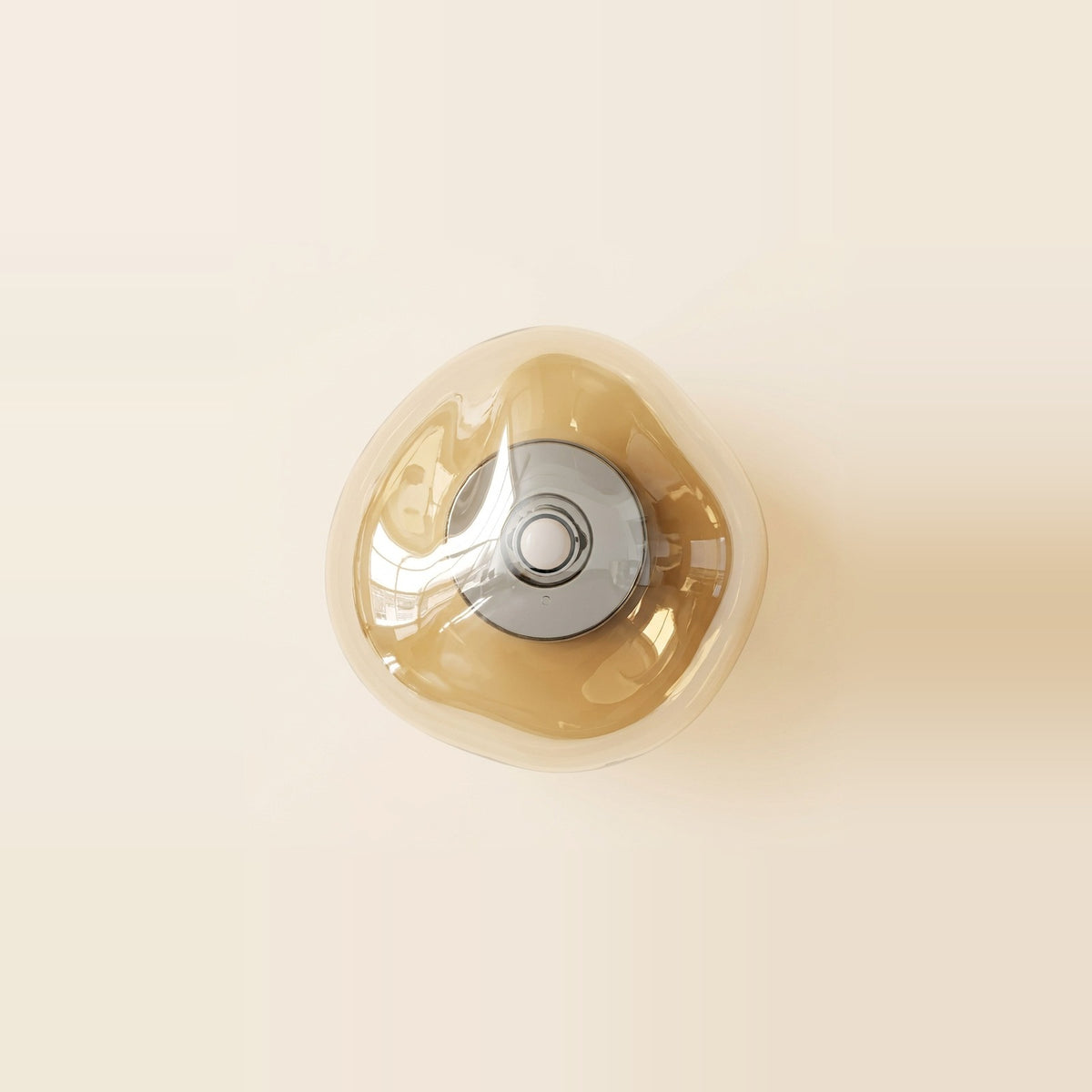Amber glass wall sconce with a rounded triangular shade and circular silver fitting mounted on a pale cream wall.