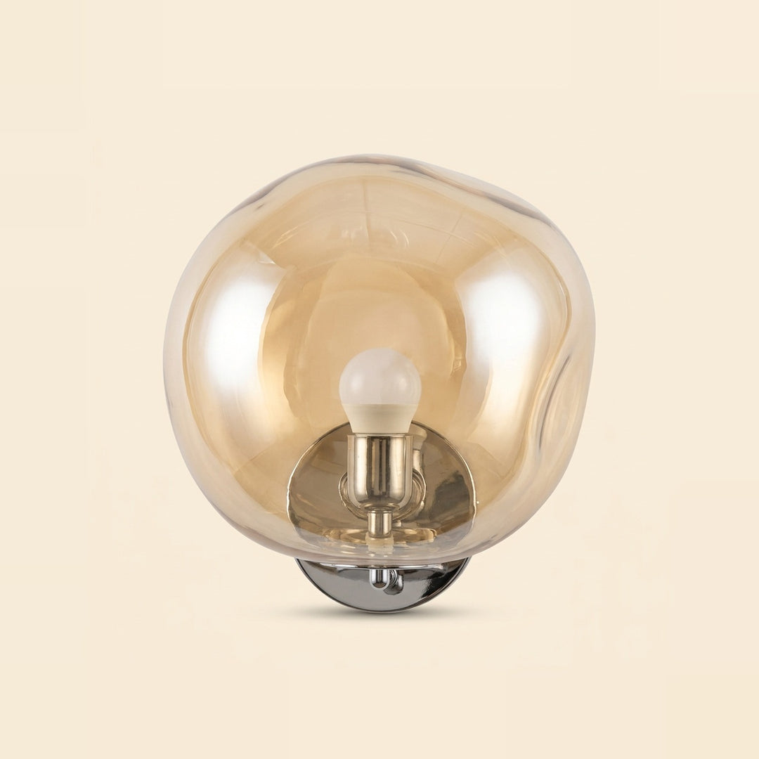 Amber glass wall sconce with an uneven rounded shade, visible upright bulb and polished silver base against a cream background.